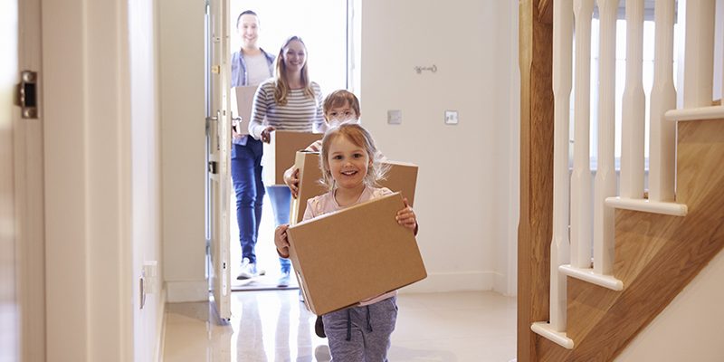 Family Carrying Boxes Into New Home On Moving Day family carrying boxes into new home