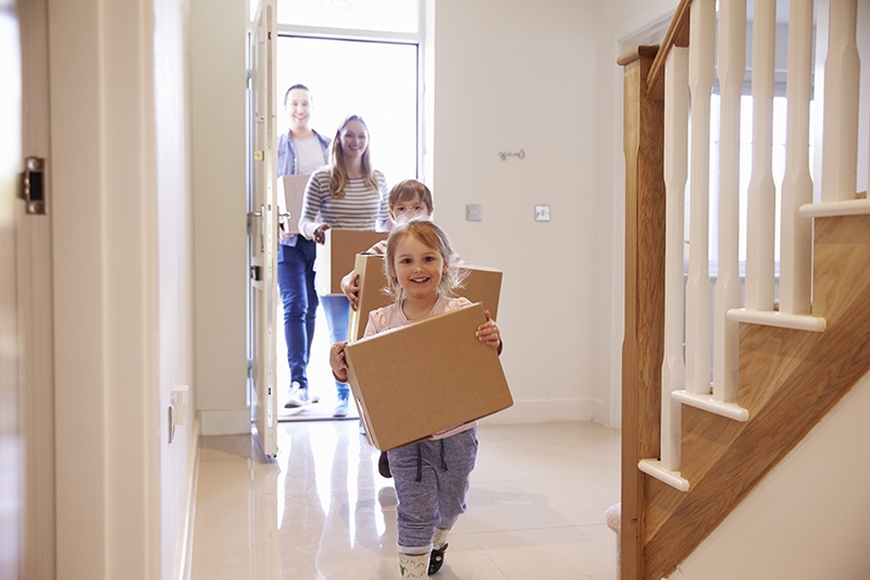 family carrying boxes into new home