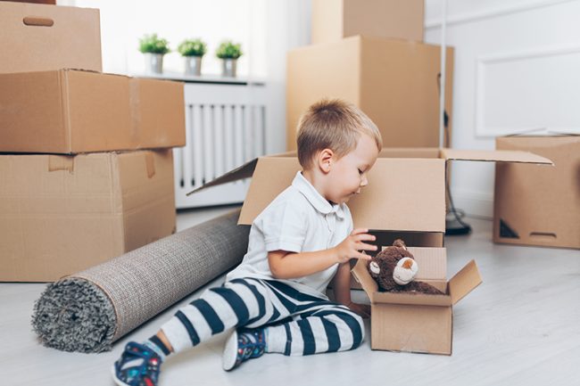 Cute toddler helping out packing boxes toddler on floor with moving boxes