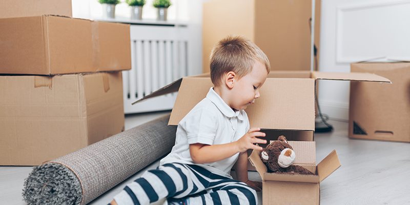 Cute toddler helping out packing boxes toddler on floor with moving boxes